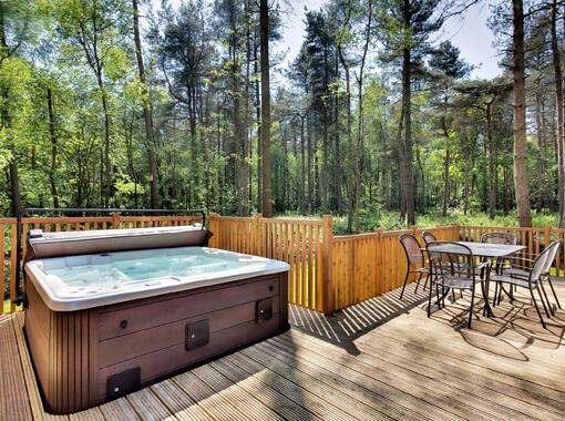 outdoor hot tub on lodge verandah surrounded by pine trees