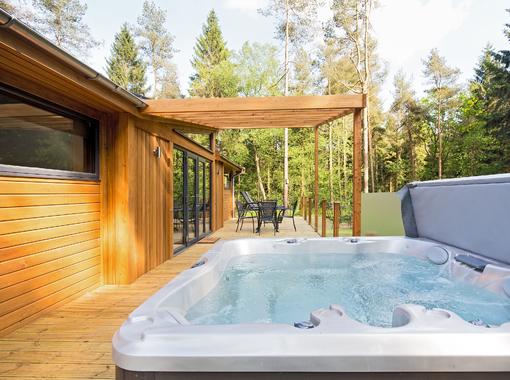 outdoor hot tub on lodge verandah surrounded by pine trees