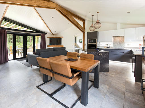 Large open plan lounge dining & kitchen area with modern dining table and feature oak beams