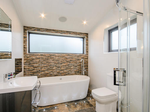 Modern bathroom with tile feature wall behind free standing bath