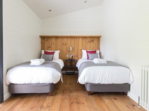 Twin bedroom with crisp white bedding and feature wooden headboard