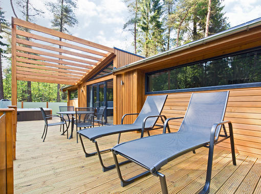 large decking area with relaxing sun loungers, table & chairs and hot tub with brise soleil