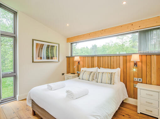 Double bedroom with crisp white bedding and feature headboard. Full width feature window above bed head.