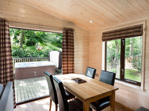 Dining area with verandah doors opening out on to decking with outdoor hot tub