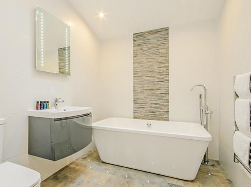 Stylish bathroom with freestanding bath and tile feature wall