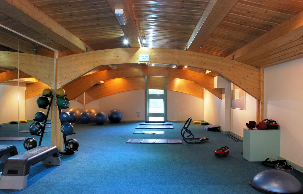 Stretch room in leisure centre with large mirrored wall, fitness balls and free wights