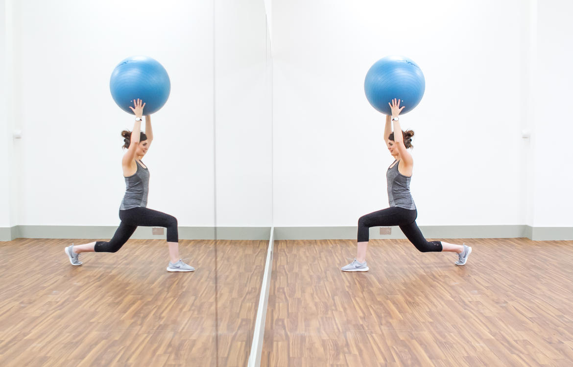 Lady in fitness studio doing exercises with gym ball in front of mirrored wall
