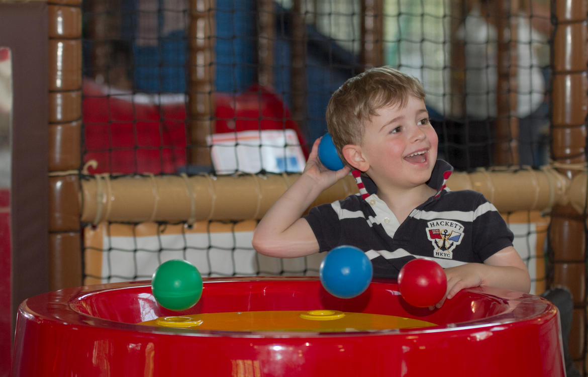 Young boy having fun with the ball machine in the toddler area