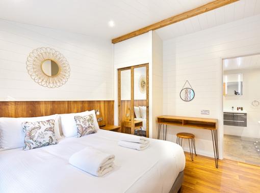 Light and airy double bedroom with crisp white bedding, door open on to en suite bathroom
