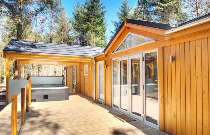 Large lodge with dining furniture and trees behind 