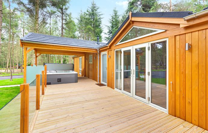 Large lodge with dining furniture and trees behind 