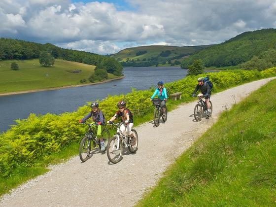 Family cycling along a path at the side of the ladybower reservoir