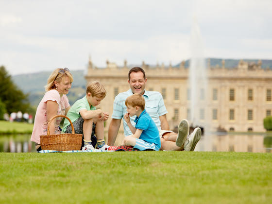 Family having a picnic next to the emperor fountain at Chatsworth with the House in the background
