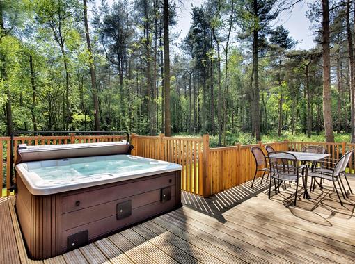 Outdoor hot tub on the verandah of a lodge within a woodland setting
