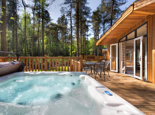 Outdoor hot tub on the verandah of a lodge within a woodland setting