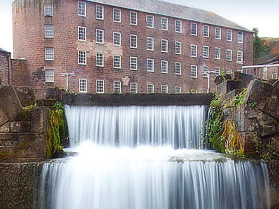 Cromford mill set in the background with waterfall in the forefront