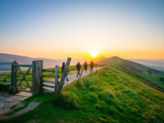 Group walking along the ridge at Mam Tor in the sunset