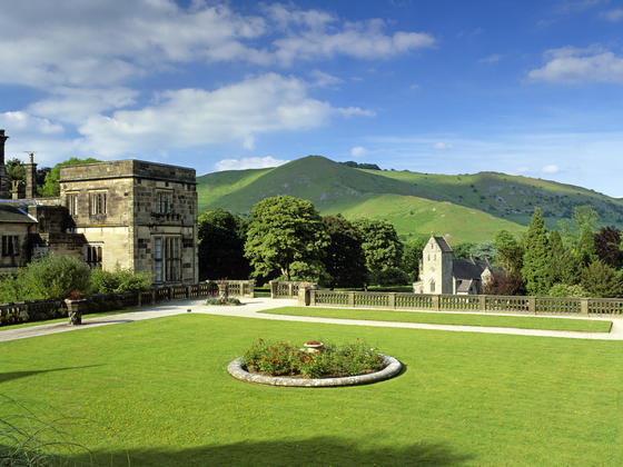 Beautiful gardens of Ilam Hall with rolling hills in the backgound