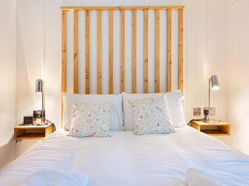 Double bed with feature wooden headboard and warm glow bedside table lamps
