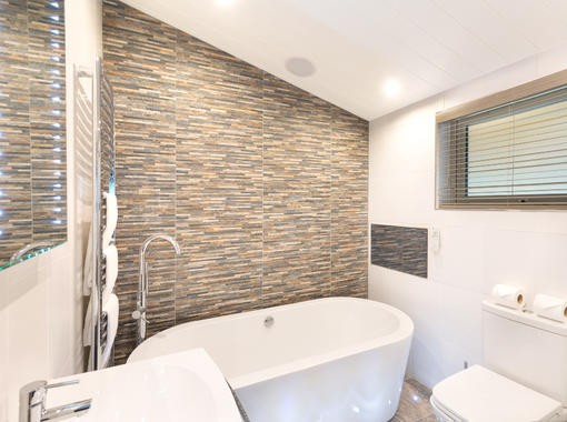 Modern bathroom with large freestanding bath and feature tile wall