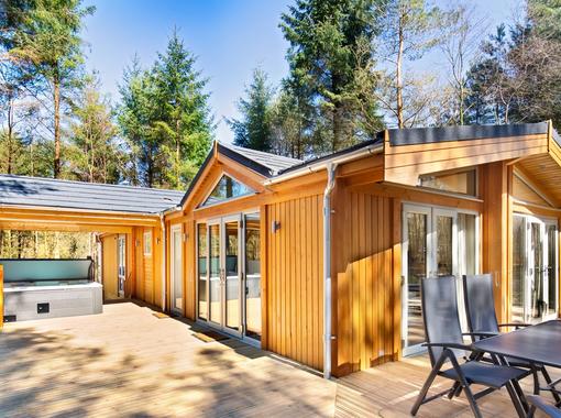 Spinney exclusive lodge with large verandah showing outdoor hot tub under wooden canopy and outdoor furniture for alfresco dining