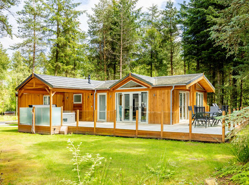 Spinney exclusive lodge with large verandah showing outdoor hot tub under wooden canopy and outdoor furniture for alfresco dining