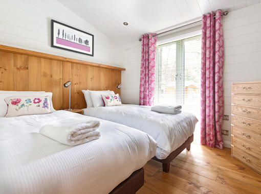 Stylish twin bedroom with crisp white bedding and pink curtains to the full height windows