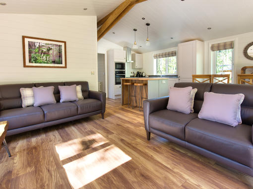light and airy interior with sun shining onto wooden floor of open plan lounge dining and kitchen area