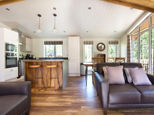 light and airy interior with sun shining onto wooden floor of open plan lounge dining and kitchen area