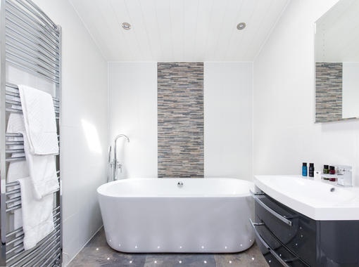 freestanding bath with feature tiles, chrome towel radiator and vanity unit with mirror over