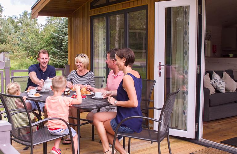 Family enjoying a meal on the verandah area of a lodge