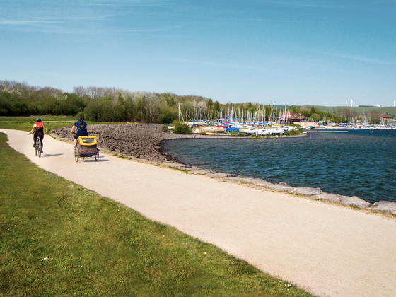 Cycling at the side of the reservoir with a trailer attached to bike