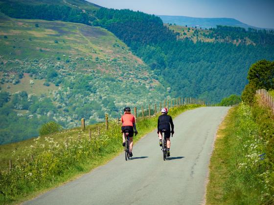 Two cyclists, cycling along a picturesque route amongst the hills