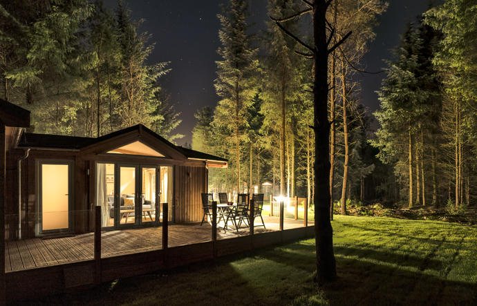 Lodge lit up at night in forest with stars in the sky